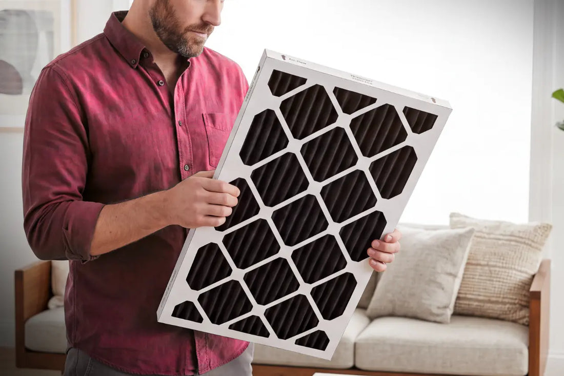 Man examining a carbon HVAC air filter in a bright living room