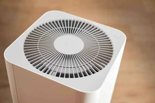 Close-up top-down view of a standalone white air purifier on a wood floor